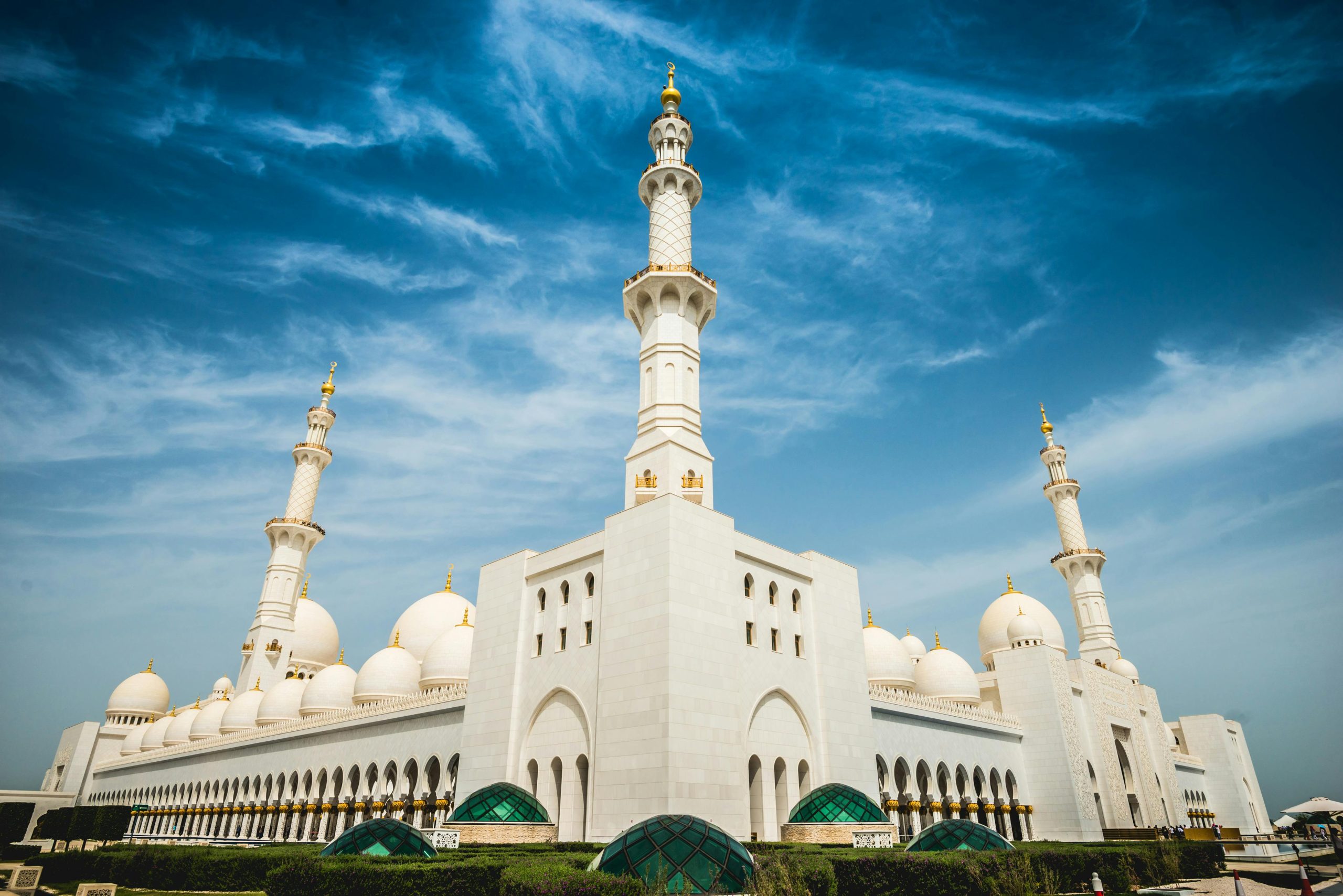 Stunning exterior shot of Sheikh Zayed Mosque with its iconic domes and minarets against a clear blue sky.