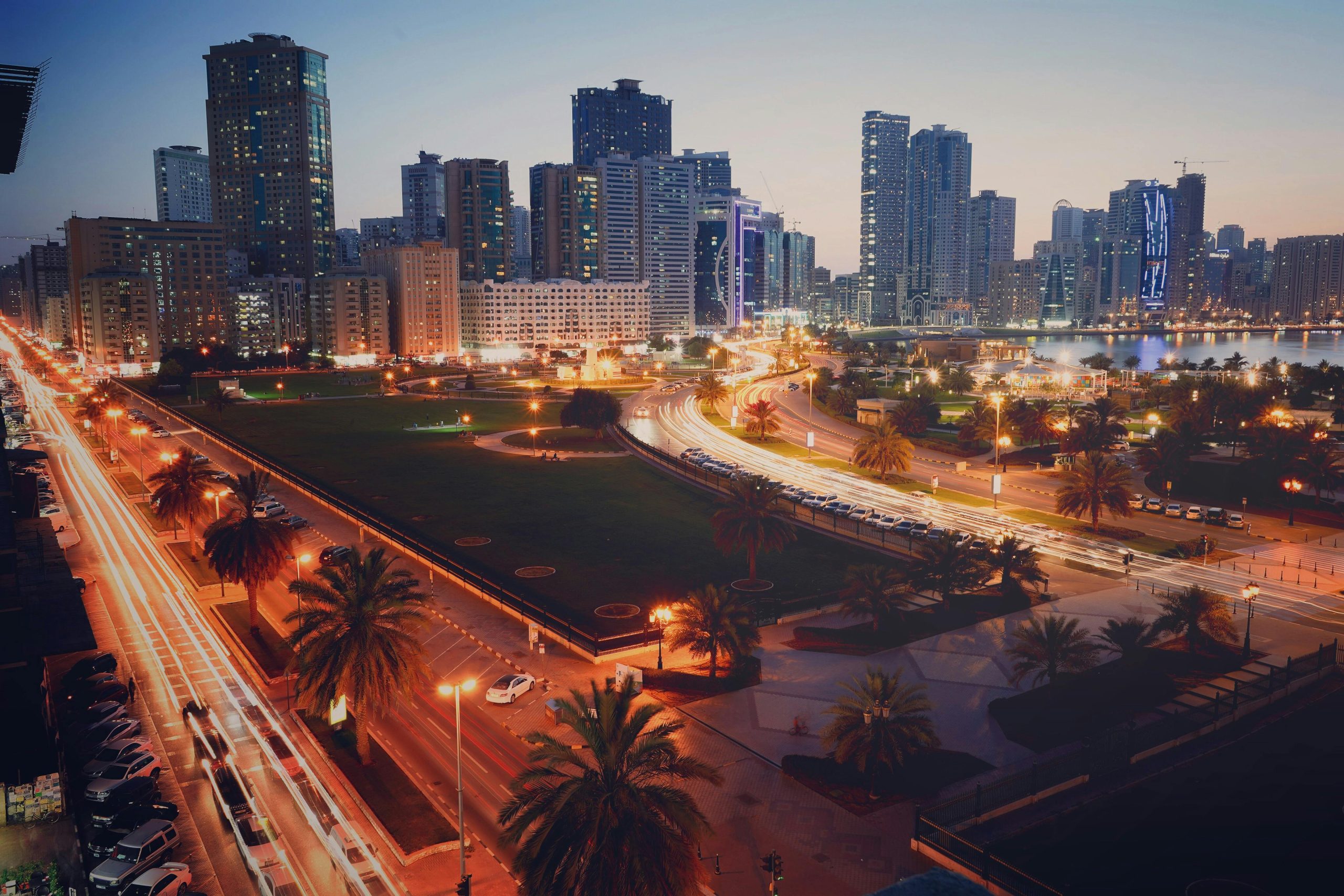 A captivating view of Sharjah cityscape at dusk featuring vibrant light trails and modern skyscrapers.